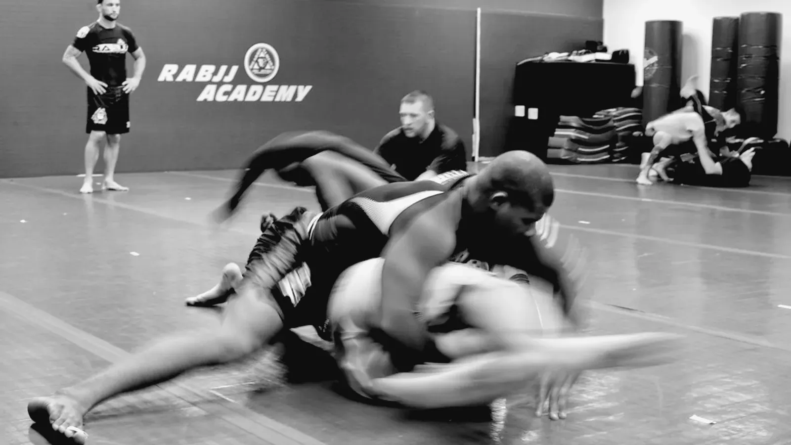 Two grapplers working from guard on the mat during an academy session.