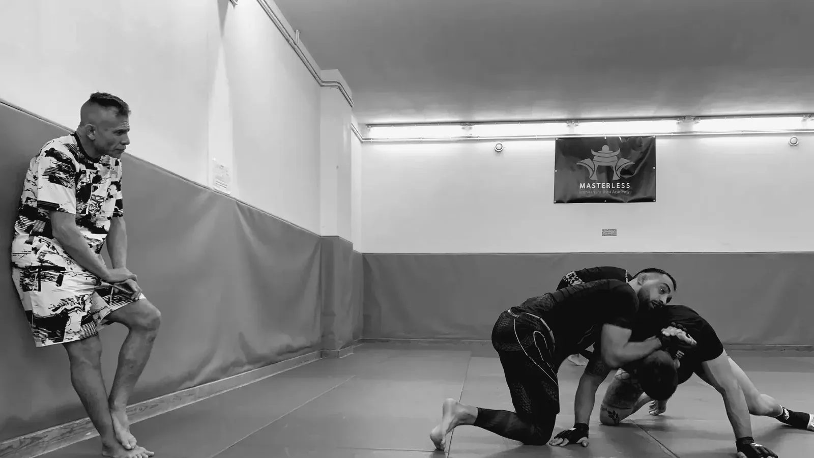 Two grapplers training on the mat in an otherwise empty academy.