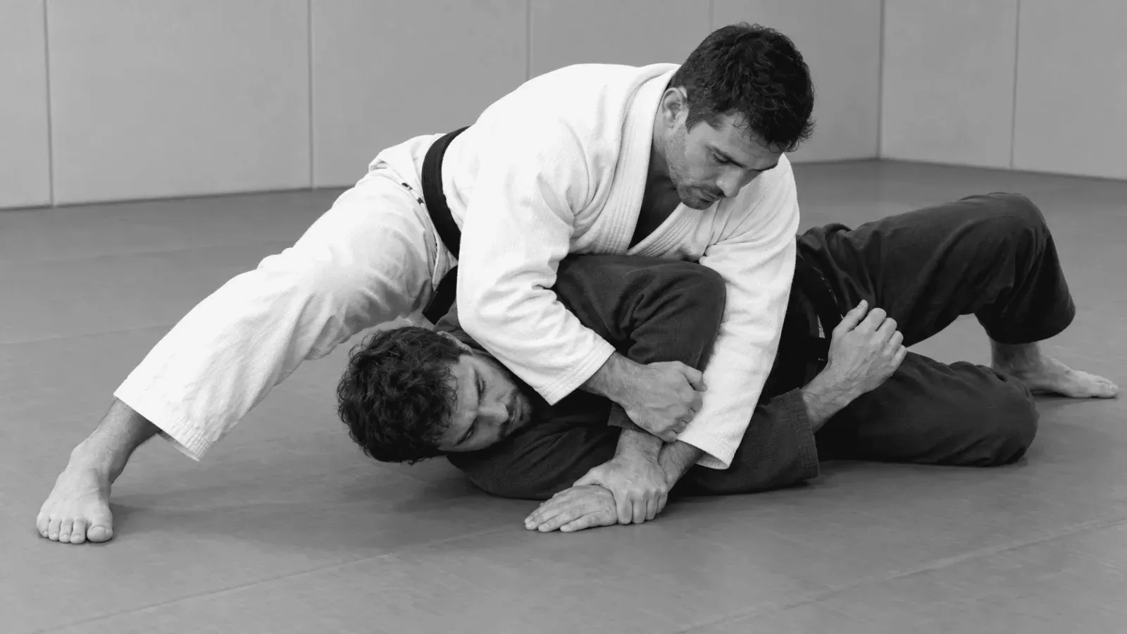 Gi partners practicing controlled arm and shoulder positioning on the mat.