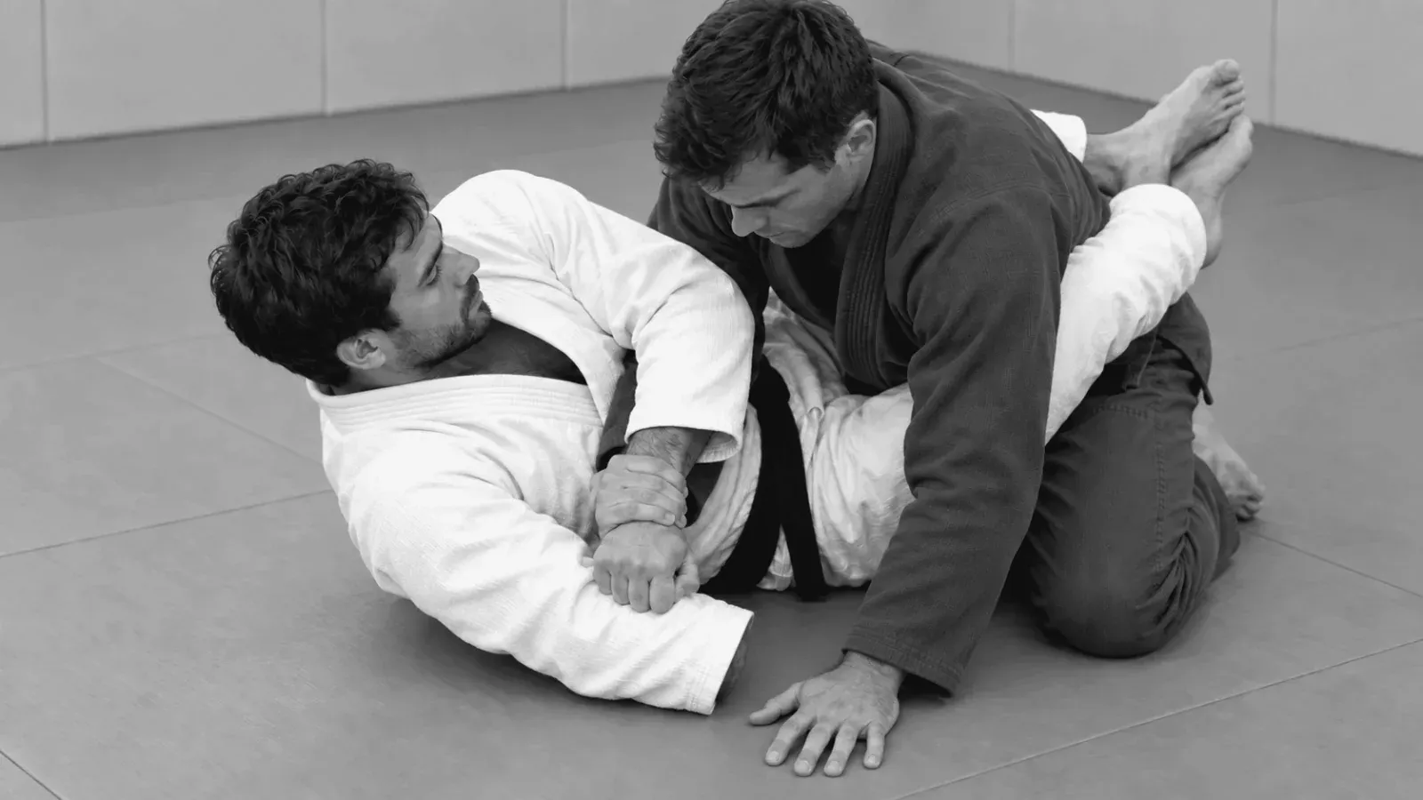 Gi partners practicing figure-four arm control from guard.