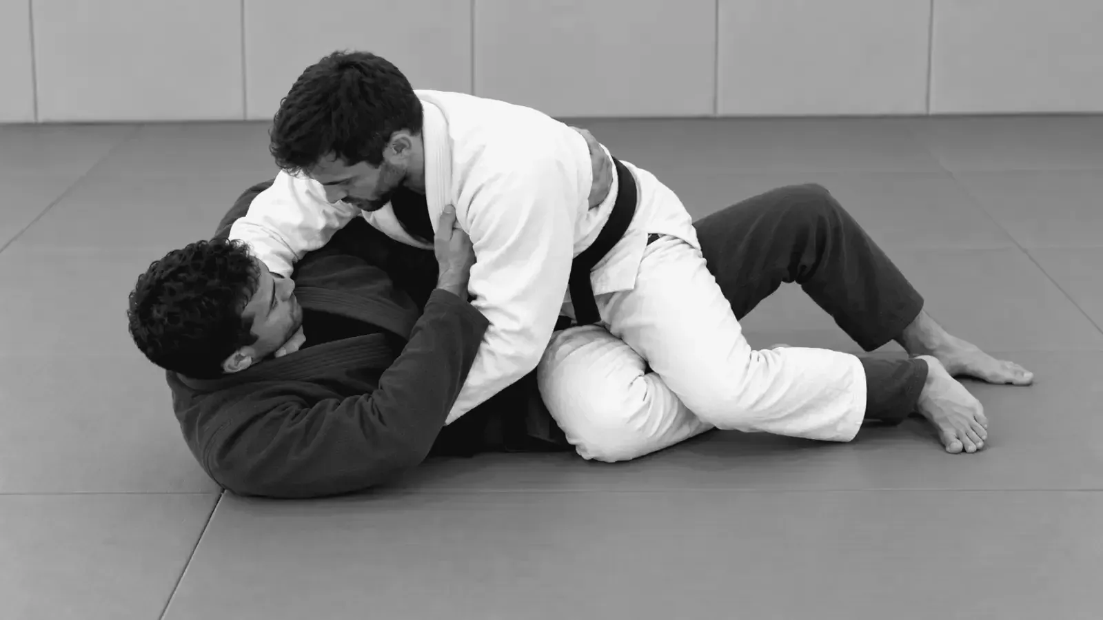 Gi partners practicing knee-cut guard passing on the mat.